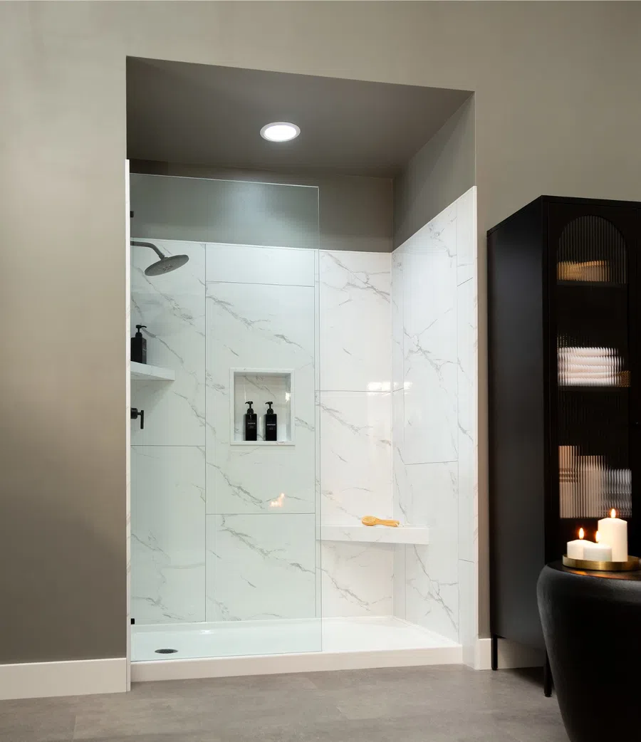 Modern bathroom with marble tile walk-in shower, white vanity, and black cabinet under soft lighting.
