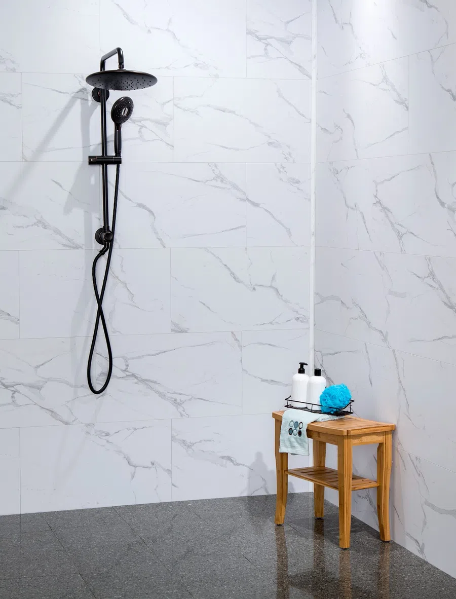 Modern shower area with black tile walls, built-in shelf holding bath products, a sponge, and a rain showerhead.
