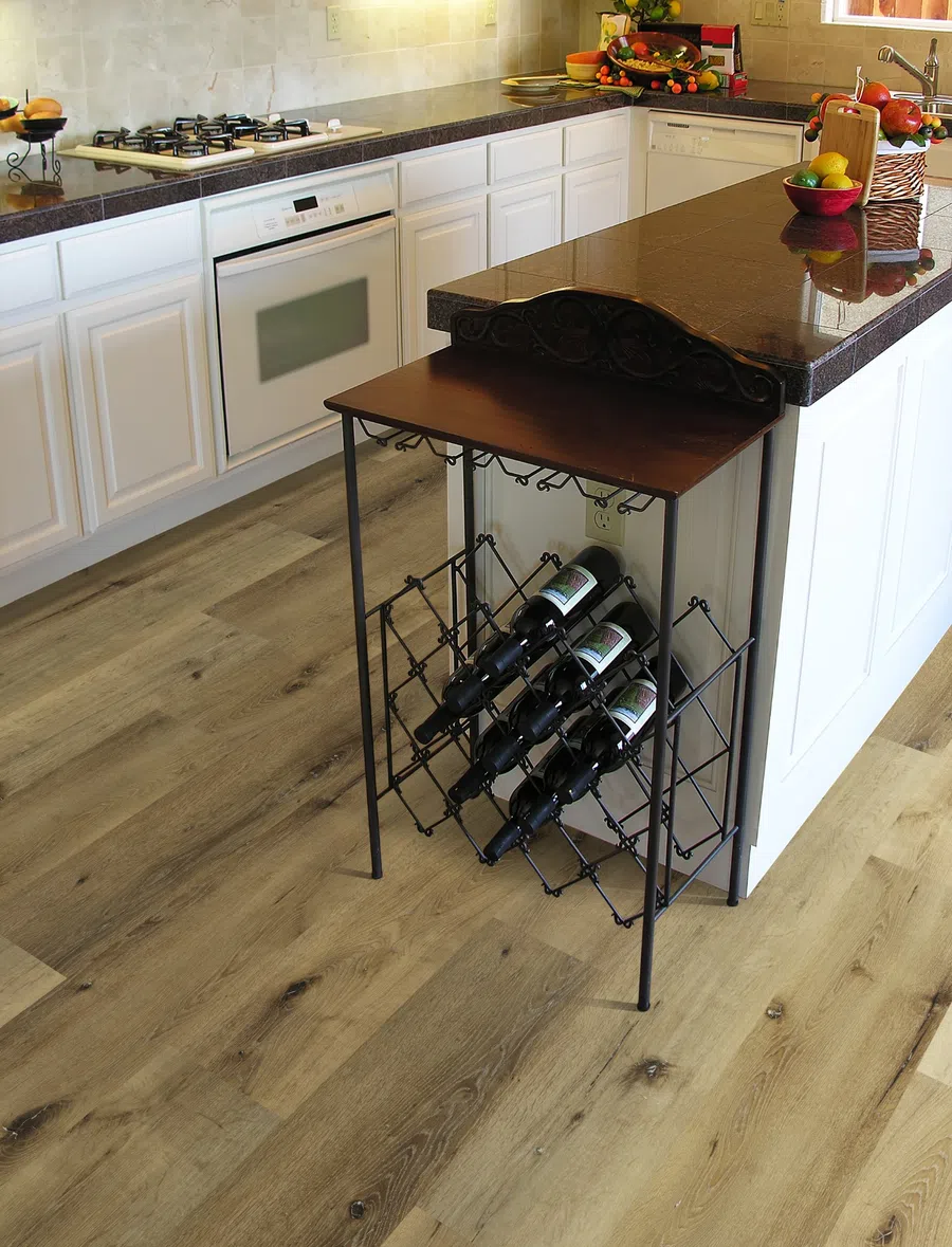 Modern kitchen with white cabinets, dark granite countertops, built-in oven, gas stove, and a wine rack holding bottles.