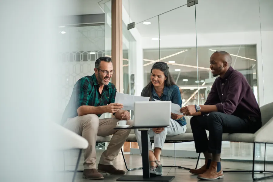 a group of people sitting on a couch looking at a laptop