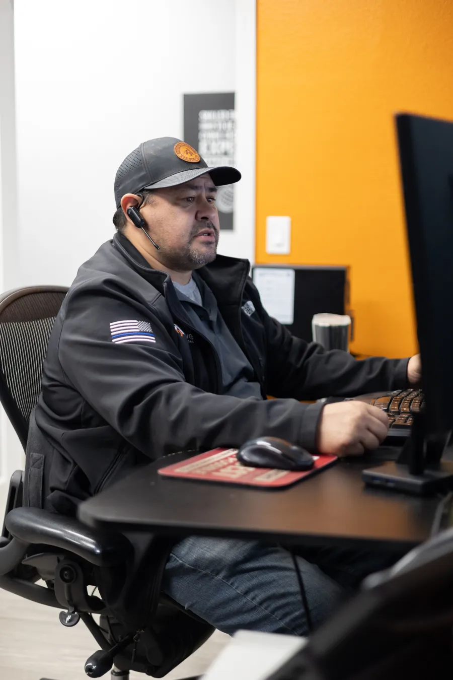 a man sitting at a desk with a computer and headphones on