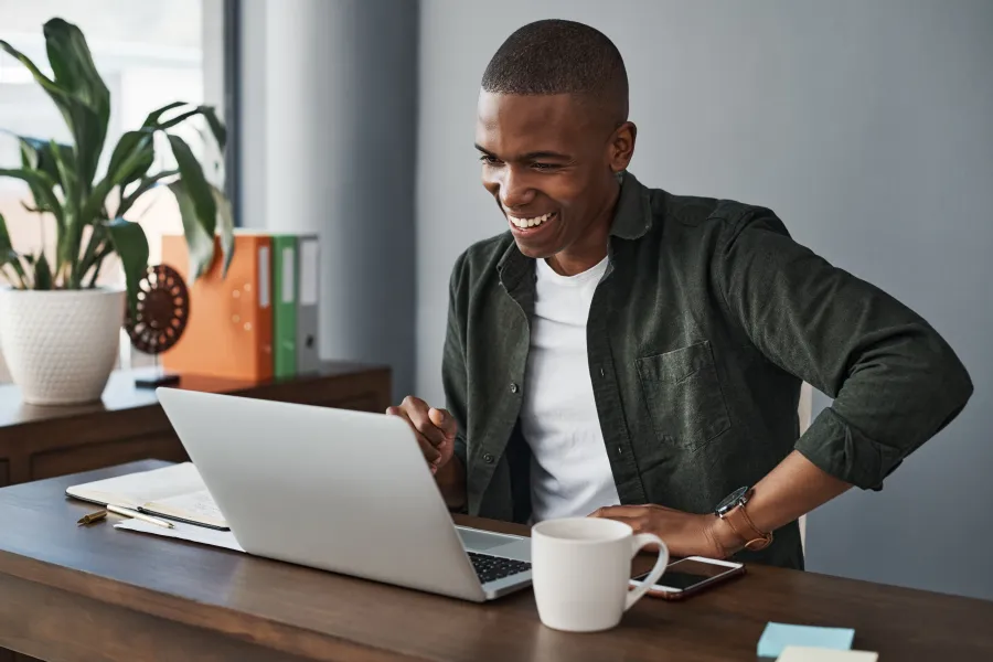 a man smiling and using a laptop