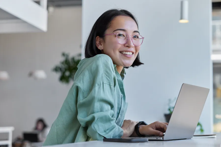 a woman smiling while using a laptop