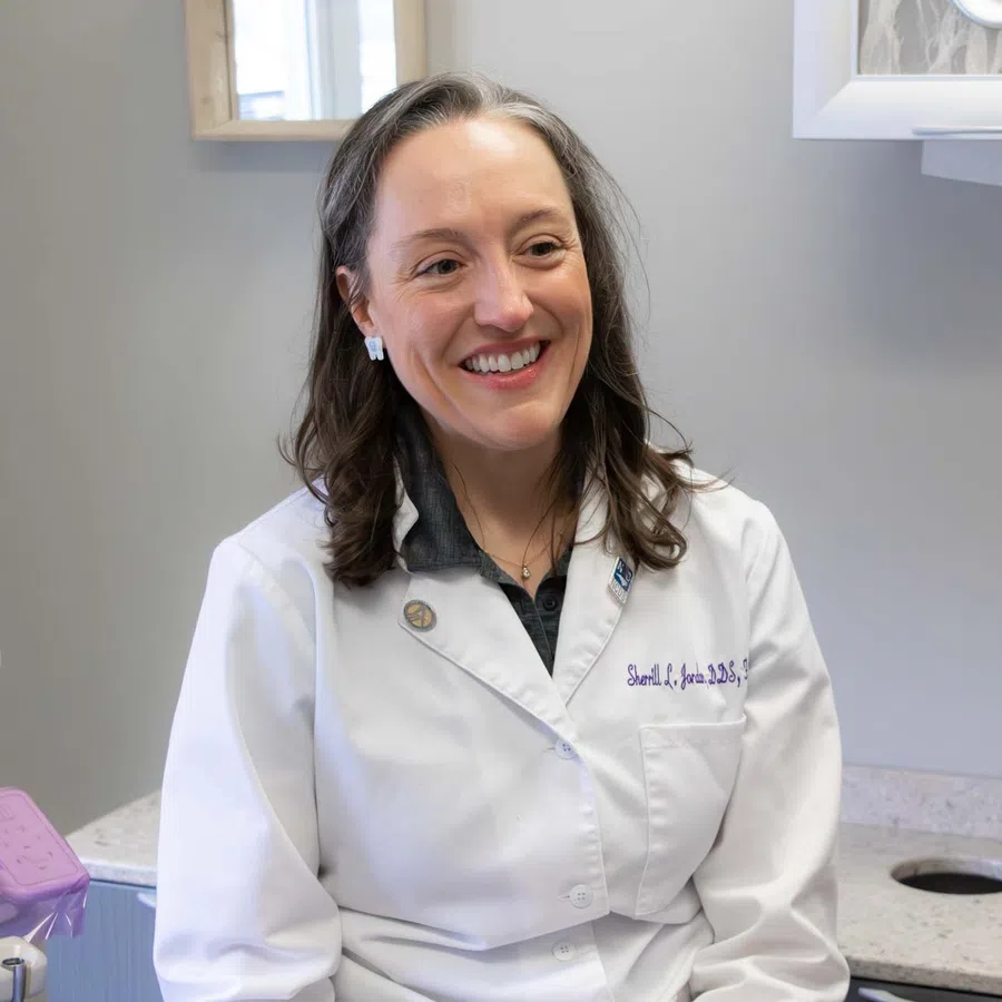 Female dentist smiling and talking to elderly male patient in the dental clinic room.