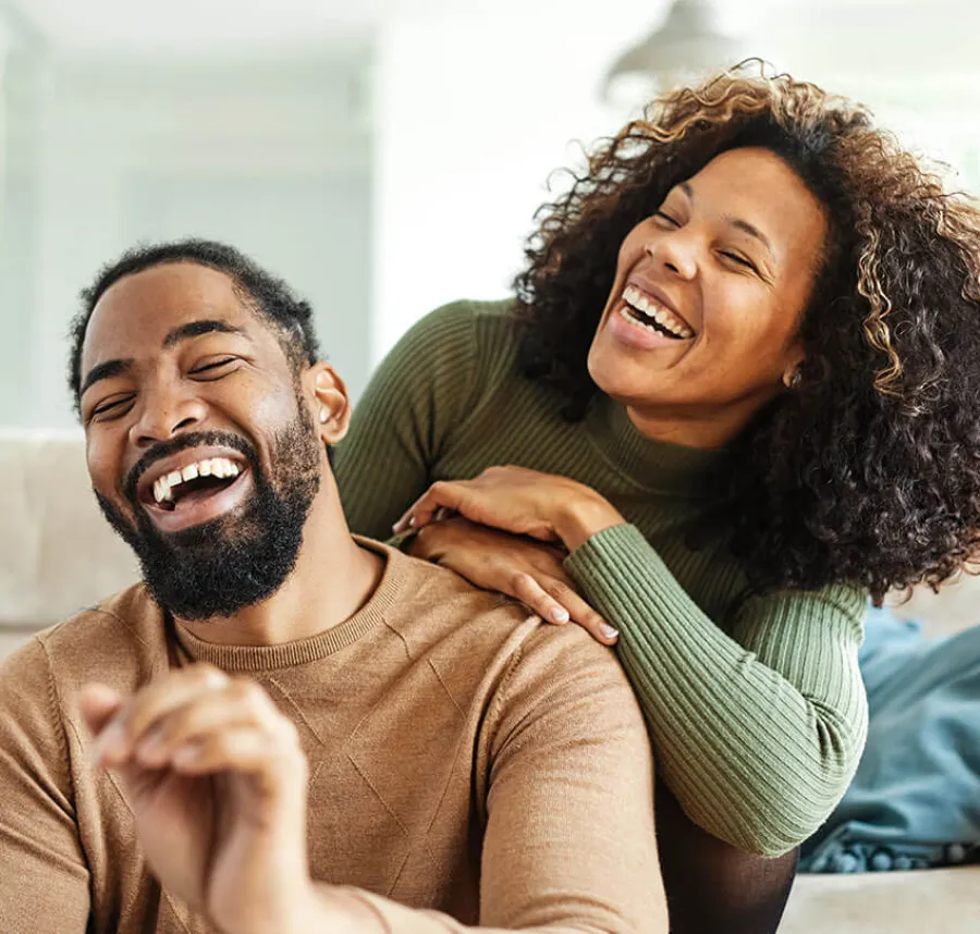 Happy couple laughing together, sharing joyful moments in a cozy indoor setting, expressing warmth and connection