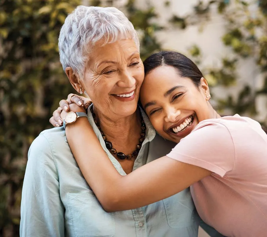 Young woman happily hugging elderly woman outdoors showing love and close family bond