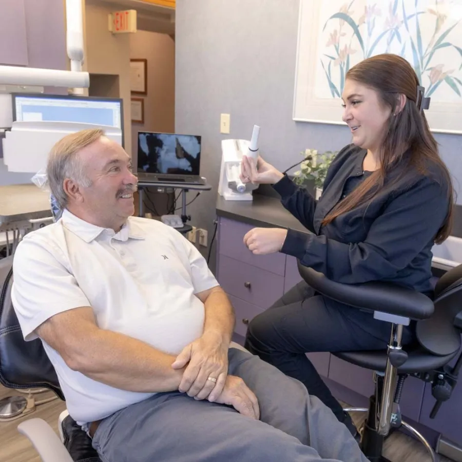 Dentist explaining dental care to a male patient in a modern dental office setting