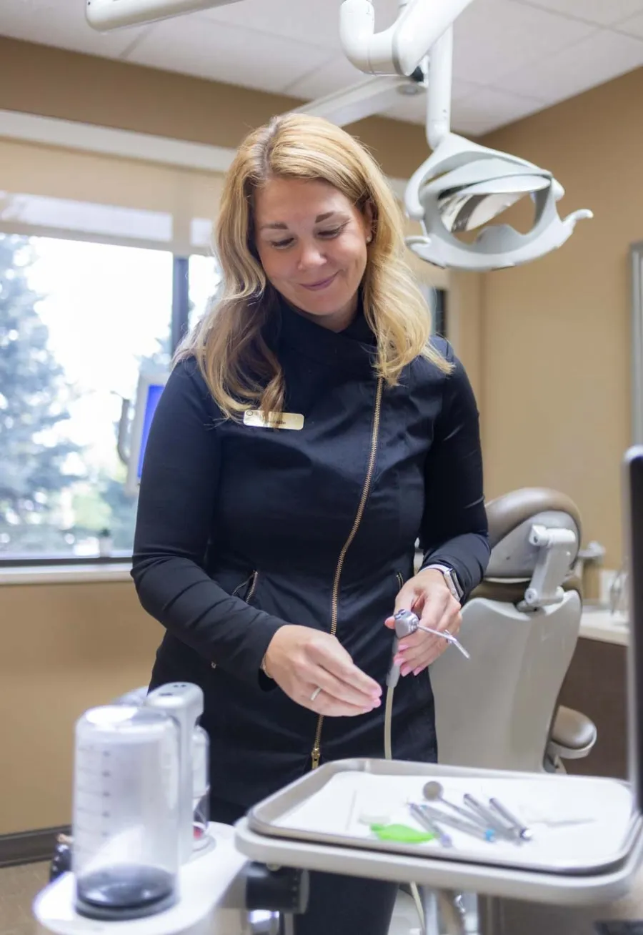 Female dentist preparing dental tools in a modern clinic with a dental chair and bright windows in the background