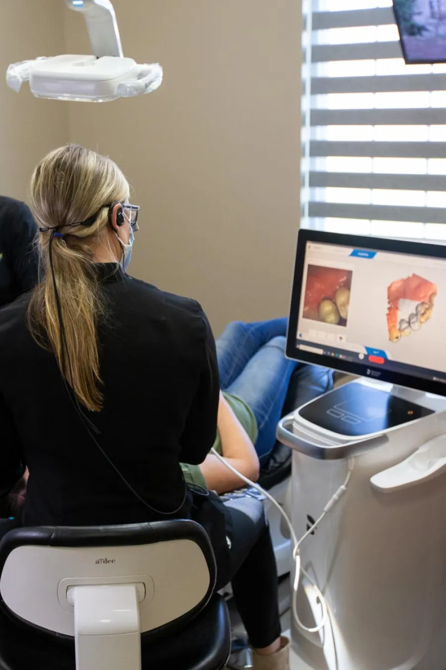 a person sitting in a chair scanning teeth