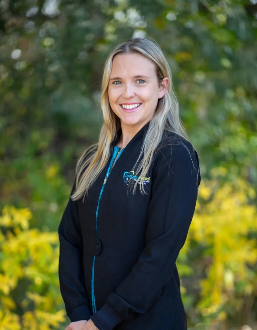 a woman smiling with trees in the background