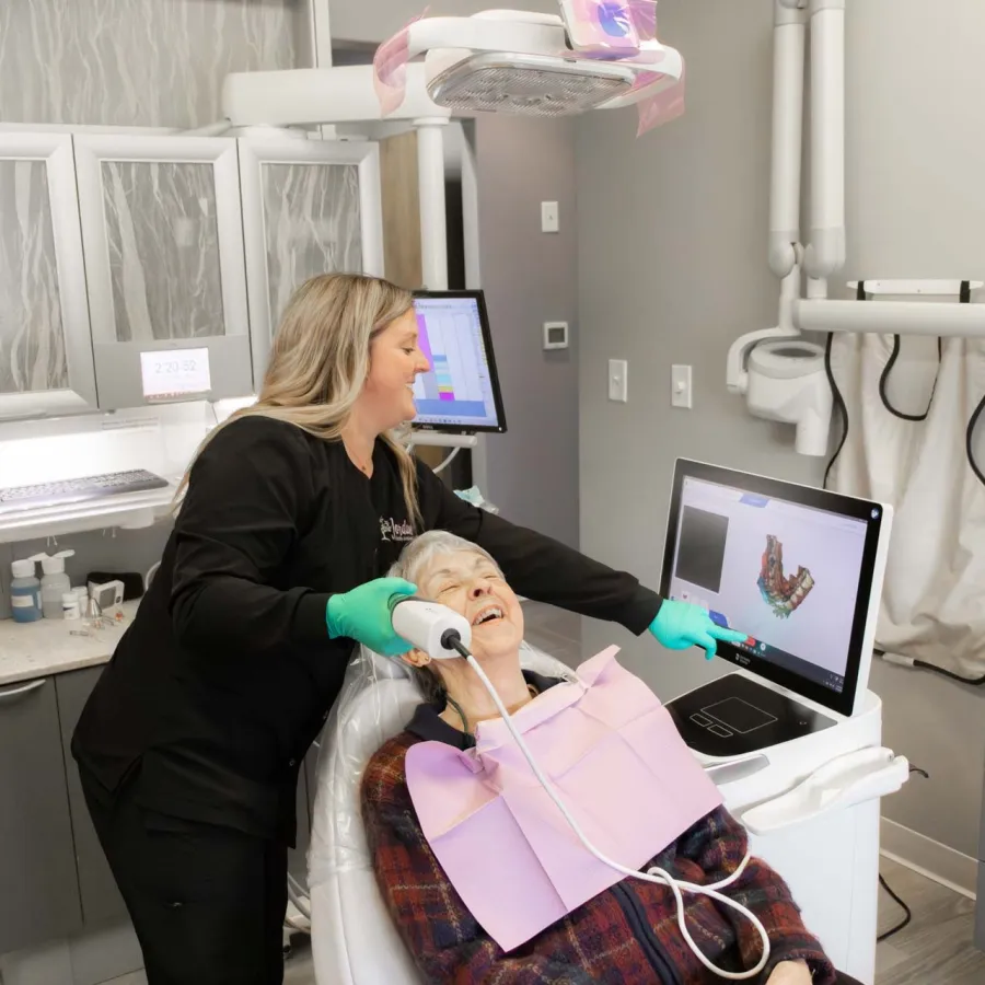Dentist using digital oral scanner on elderly patient in modern dental office during checkup.