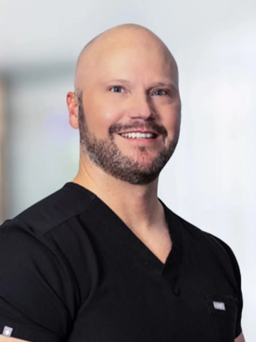 Smiling man in scrubs, showcasing a professional medical appearance and friendly demeanor.