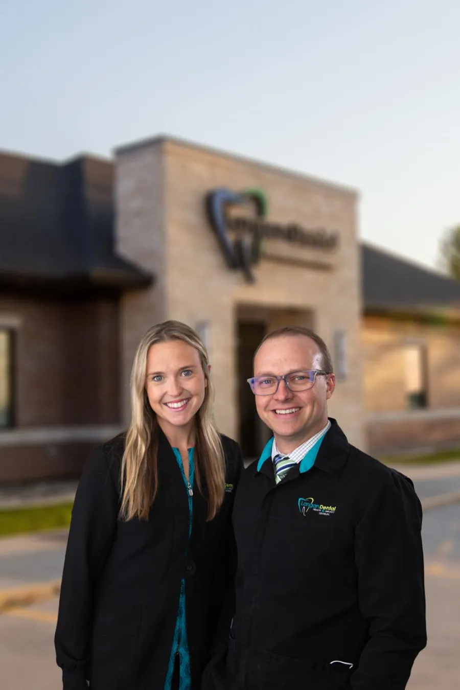 a man and woman posing for a photo in front of a building