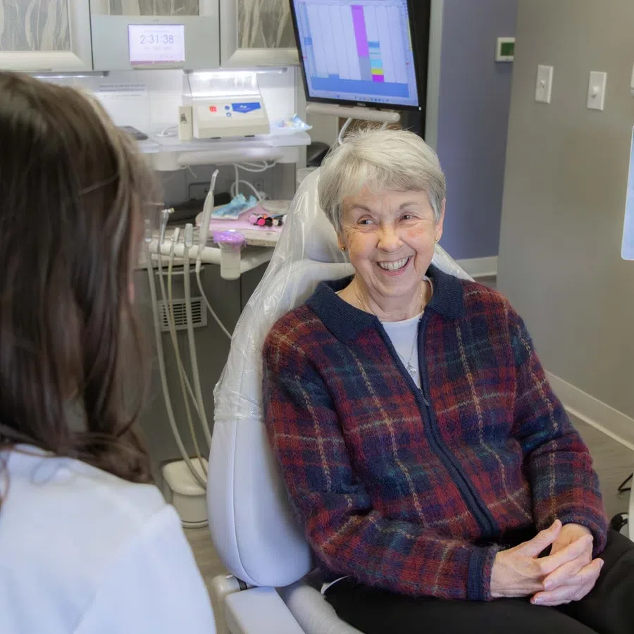 Senior woman smiling during a dental checkup with a female dentist in a modern clinic room.