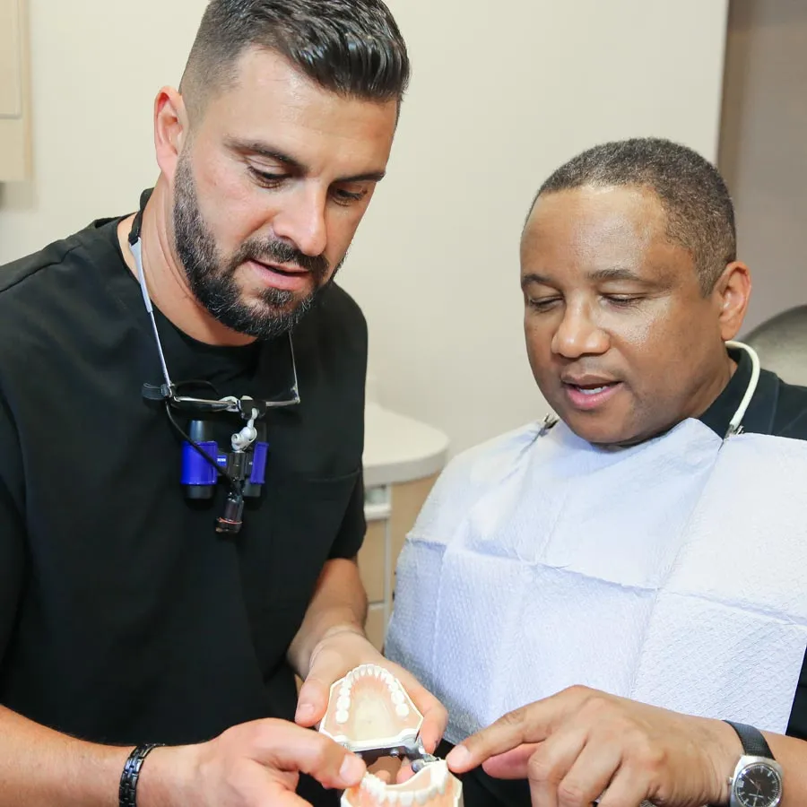 Two dentists discussing a dental model in a clinic setting, showcasing teamwork and patient care.