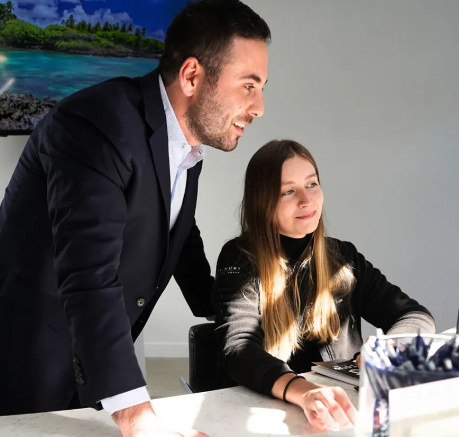 Two professionals collaborating at a desk with a beach landscape in the background.