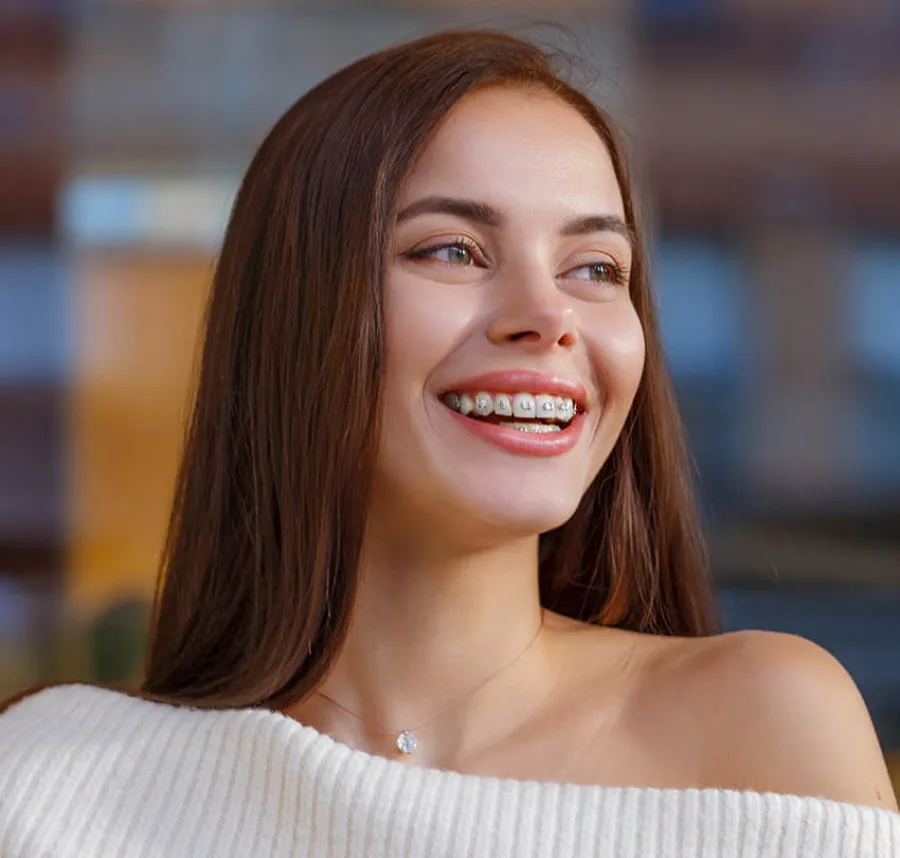 Smiling young woman with braces wearing a white off-shoulder top and a delicate necklace