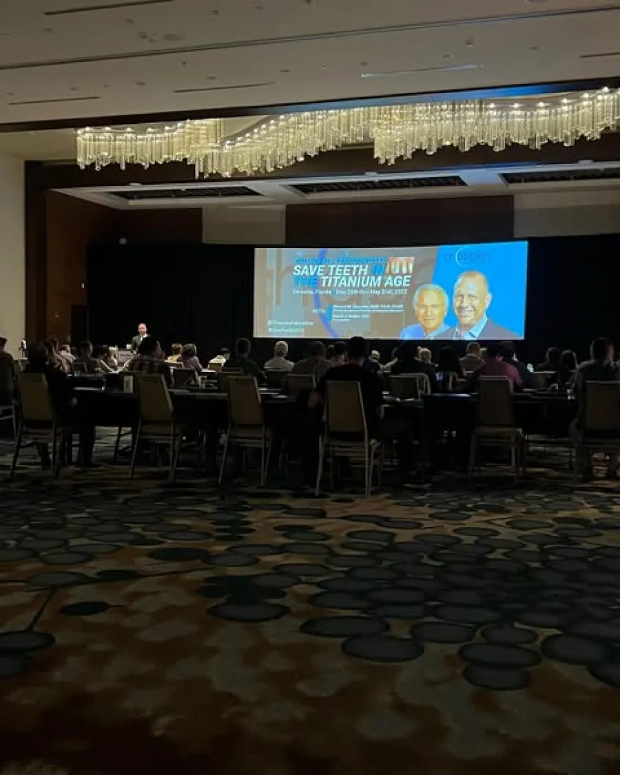 Audience seated in conference room watching presentation on saving teeth in titanium age.