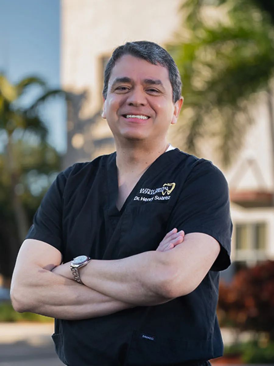 Professional headshot of a smiling woman with long dark hair wearing a red blouse and dark blazer against gray background