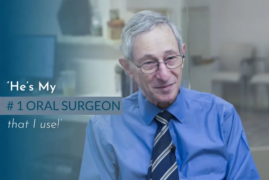 Smiling older man in glasses and blue shirt with text praising his oral surgeon in a dental office.
