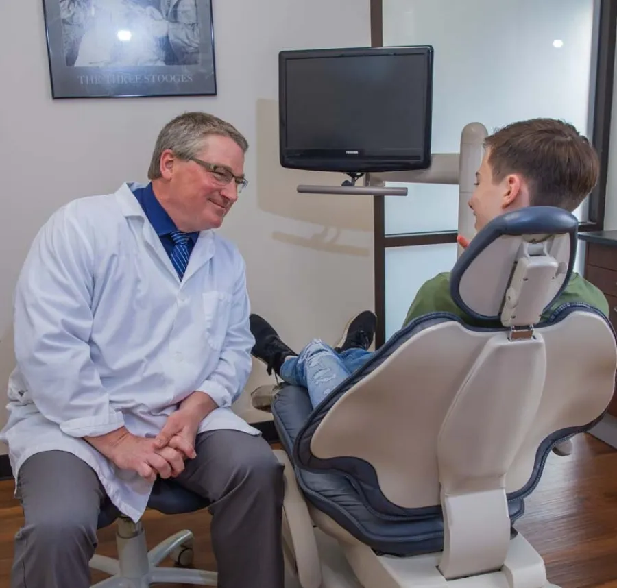 Dentist consulting with a patient seated in a dental chair in a modern clinic.