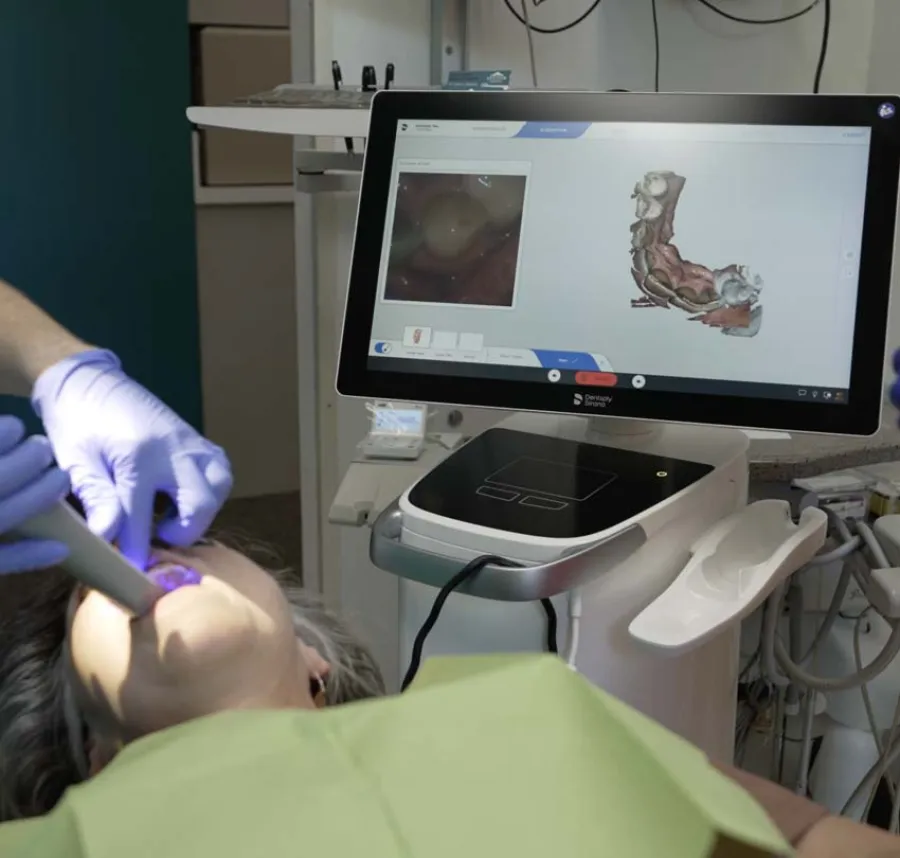 Dentist uses advanced 3D dental scanner to capture detailed images inside patient's mouth during exam.