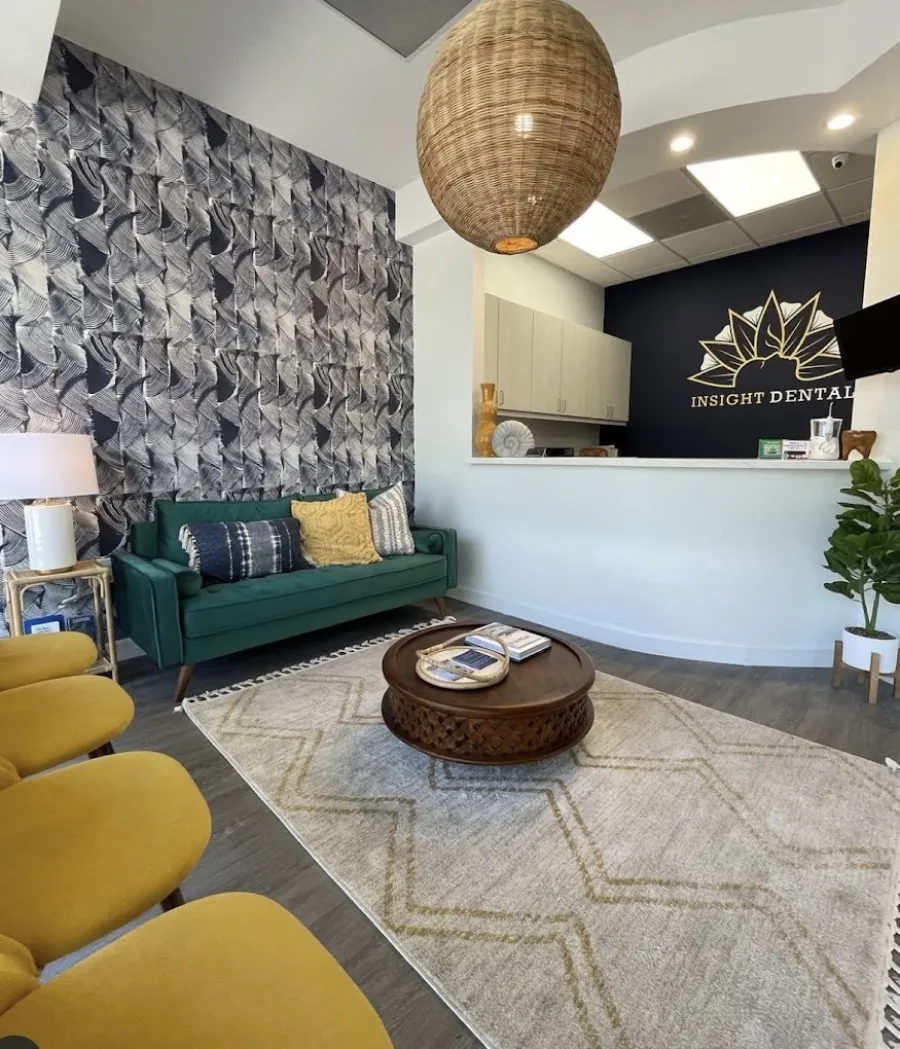 Modern dental office interior featuring green sofa, patterned walls, and round coffee table.