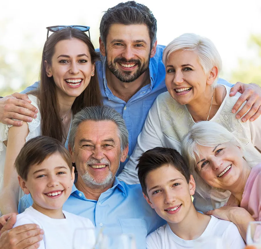 Happy multigenerational family smiling and hugging outdoors in bright natural light