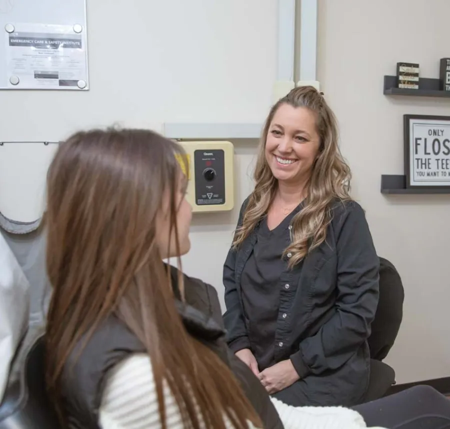 Dentist smiling and talking to female patient in a dental office with oral health decor.