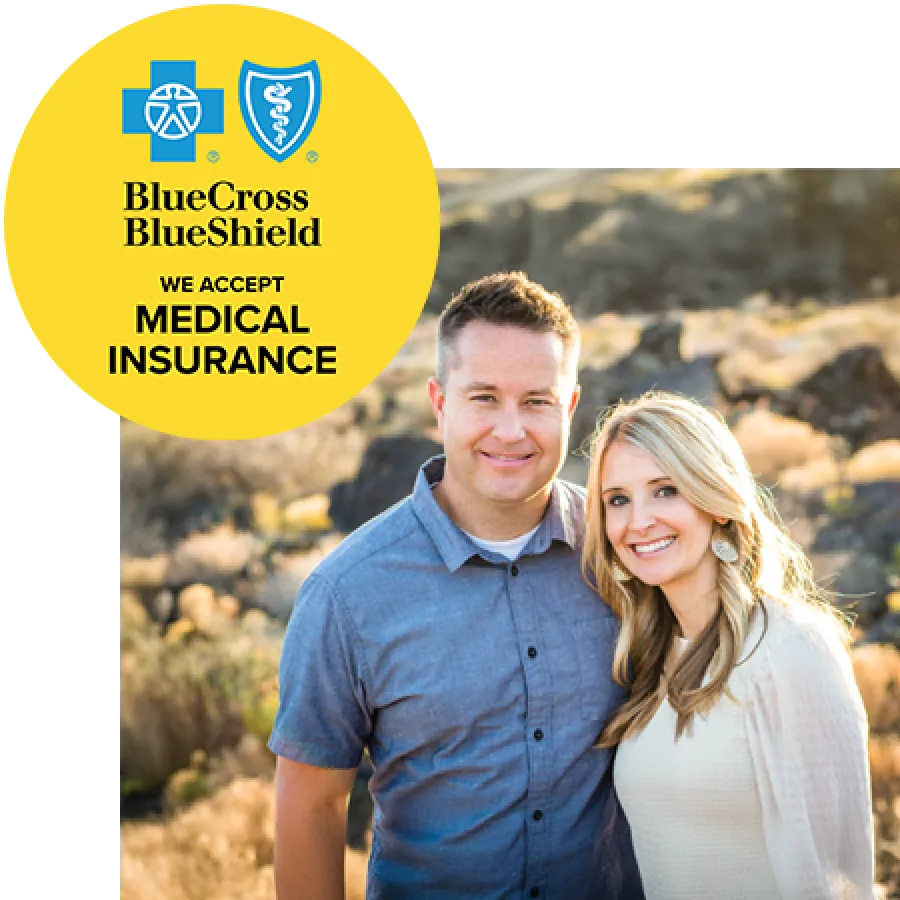Smiling couple outdoors with Blue Cross Blue Shield medical insurance acceptance badge in yellow circle.