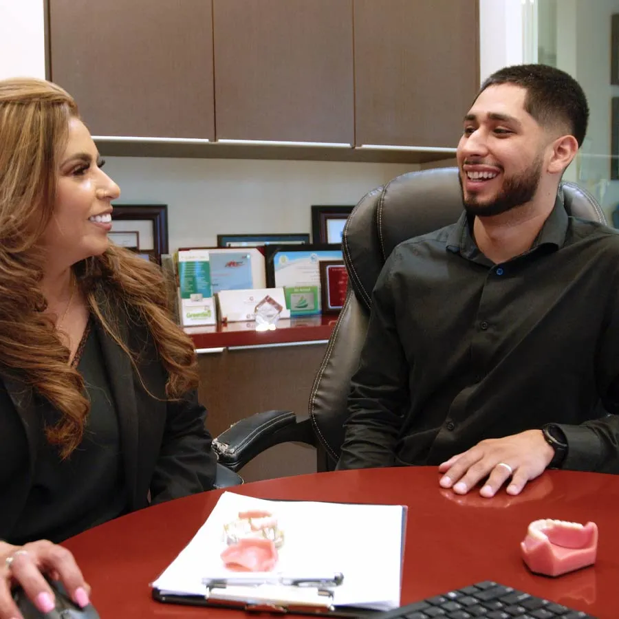 Two professionals smiling and discussing dental models in an office setting, showcasing teamwork and professionalism.