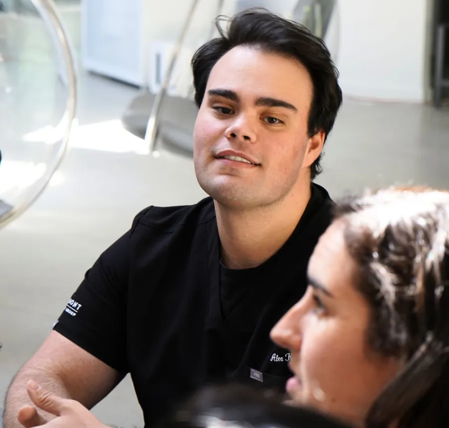A young man in a black shirt engaging in conversation in a modern setting.