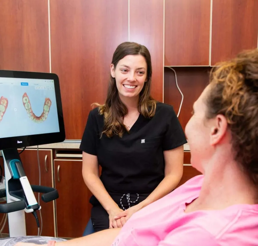 Dental professional discussing 3D teeth scan results with a patient in a modern dental office.