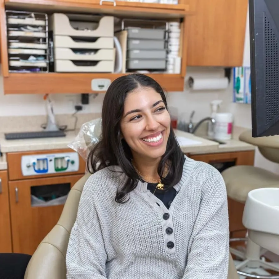 Smiling woman sitting in dental chair with dentist beside her in a modern clinic during consultation.