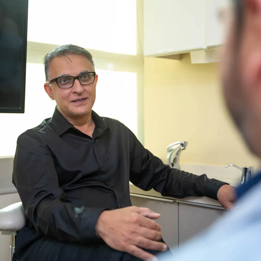 A professional man in a black shirt engaged in conversation in a modern office setting.
