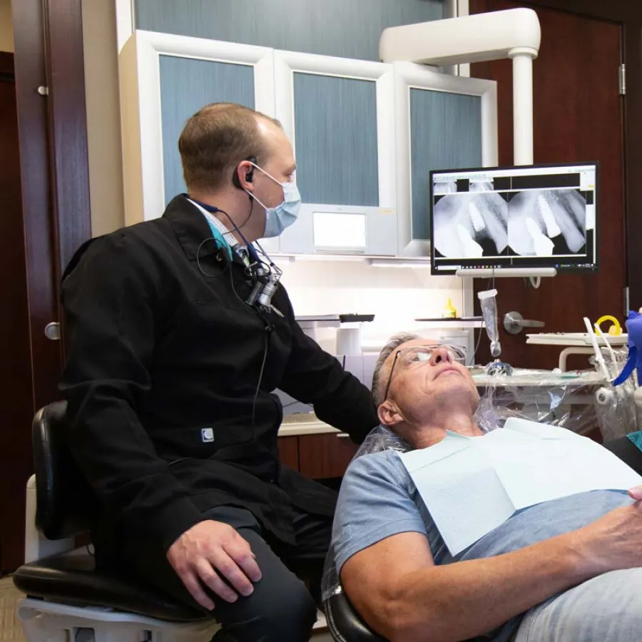 Dentist examining patient during a dental check-up with X-rays on the monitor.