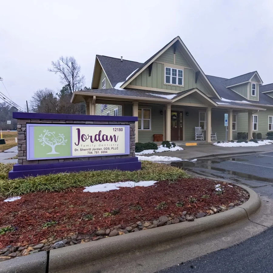 Jordan Family Dentistry office building with signage and landscaped entrance on a cloudy day with patches of snow.