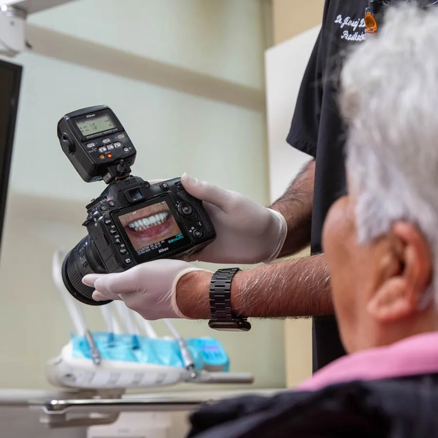 A dentist capturing a patient's smile on camera during a dental procedure.