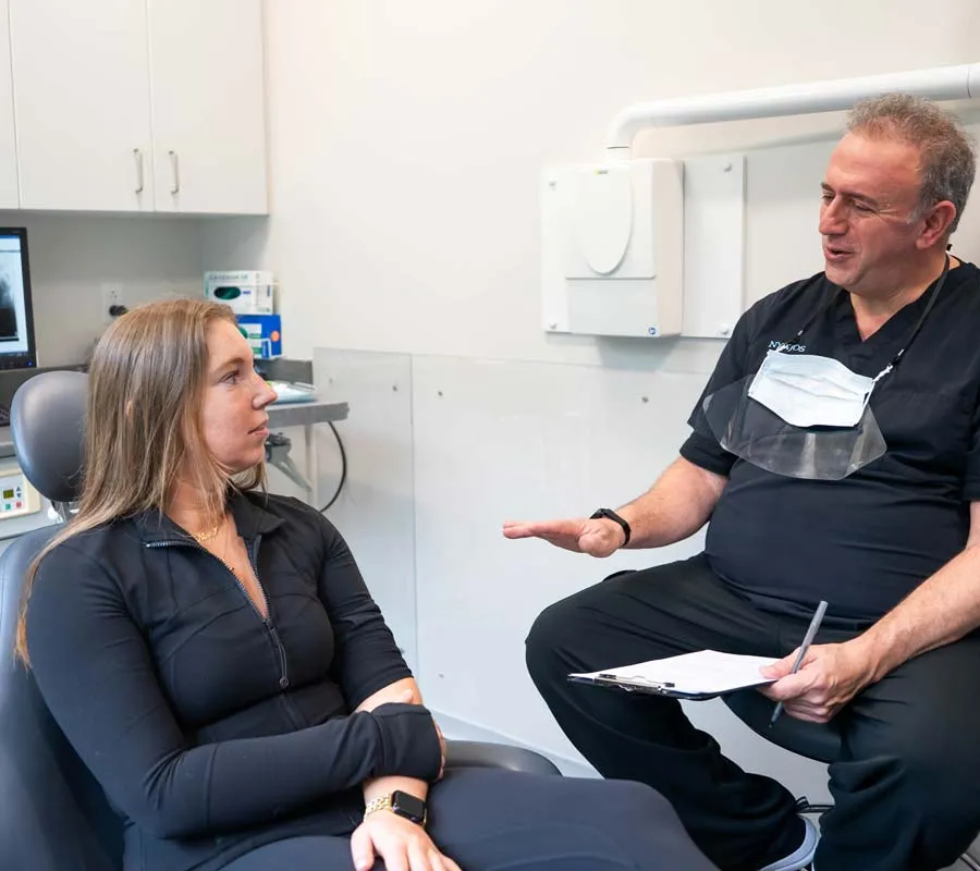 Dentist consulting female patient in dental office explaining treatment plan.