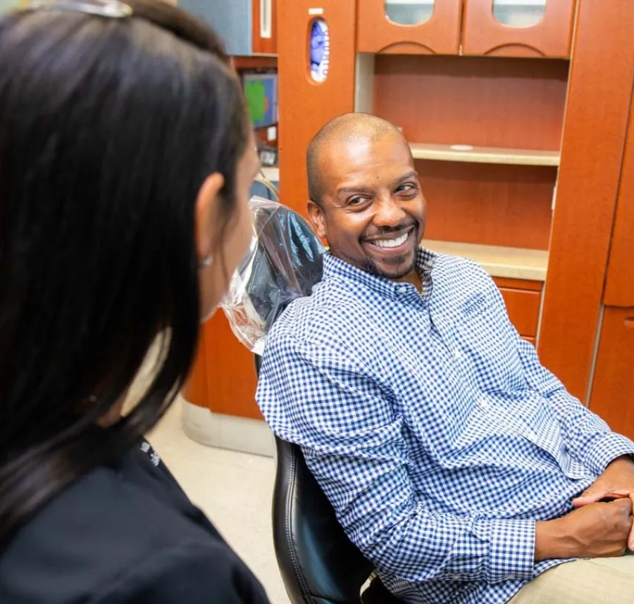 Smiling man in dental chair talking to dental professional in modern clinic setting