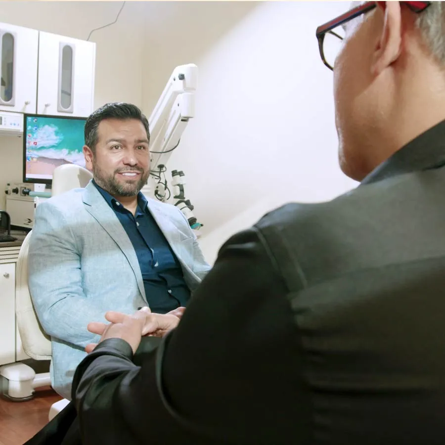 A patient smiles during a consultation with a doctor in a medical office.
