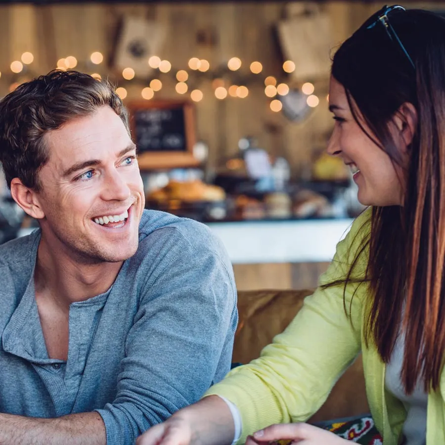 A smiling man and woman engaging in conversation at a cozy cafe.