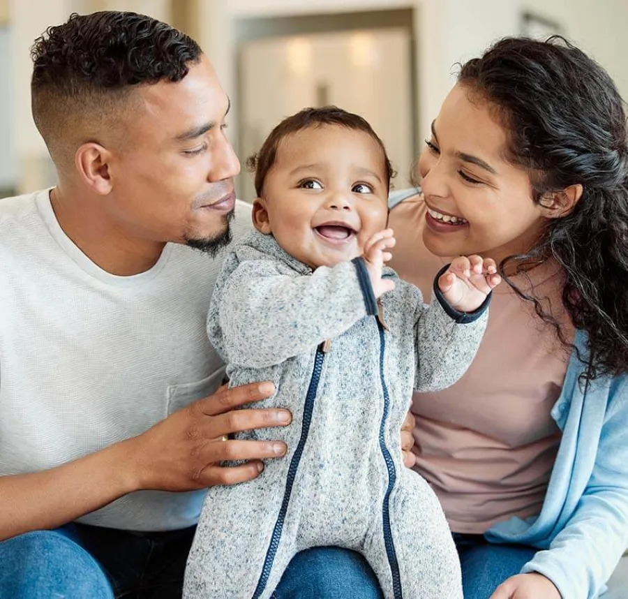 a family laughing and holding a baby