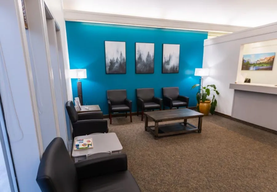 Modern office waiting area with blue walls, comfortable seating, and artistic wall prints.