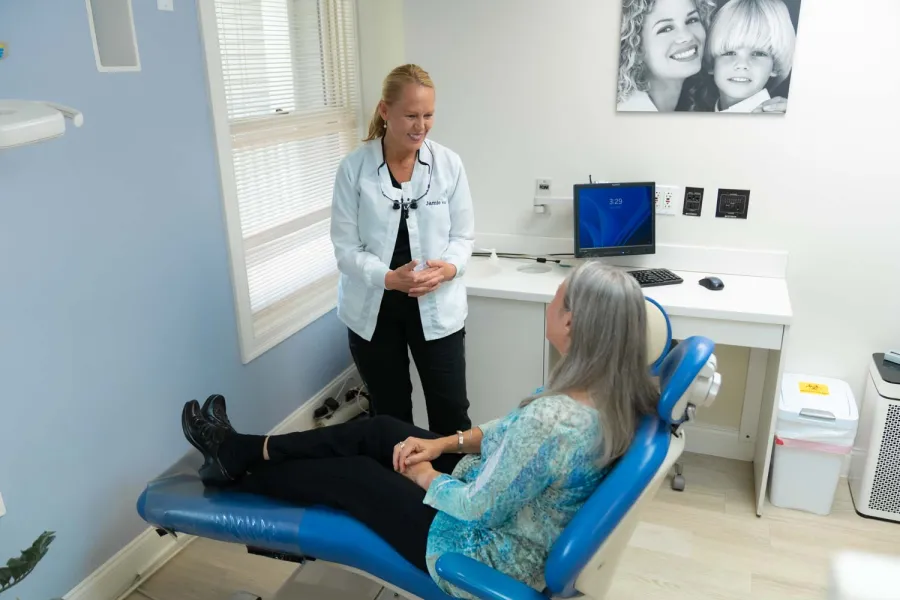 Dentist consulting with a female patient seated in a dental chair in a bright clinic room