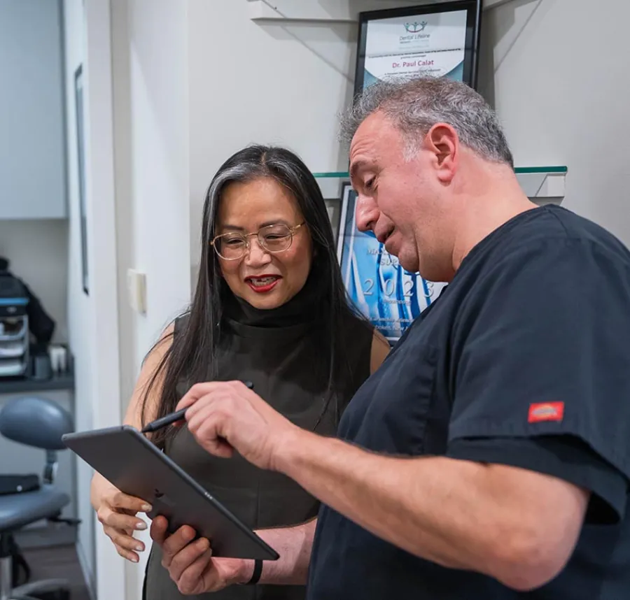 Dentist explaining treatment details on tablet to a smiling female patient in a dental office
