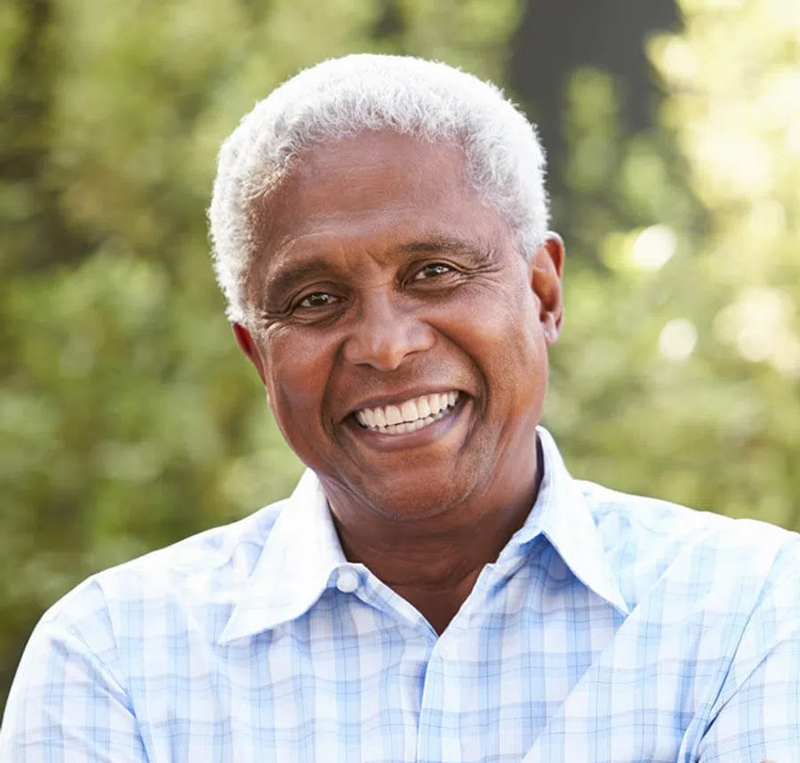 Smiling mature man with gray hair wearing a blue checkered shirt outdoors in natural light