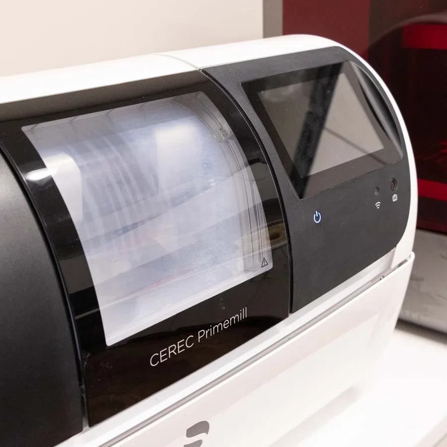 Close-up of CEREC Primemill dental milling machine with touchscreen control in a clinical setting.