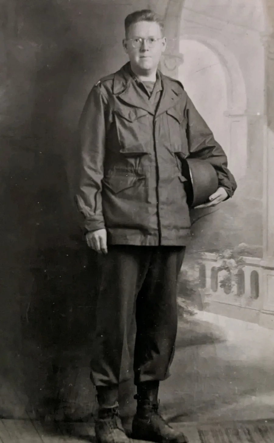 Smiling woman with brown hair and bangs in natural outdoor setting with green blurred background.