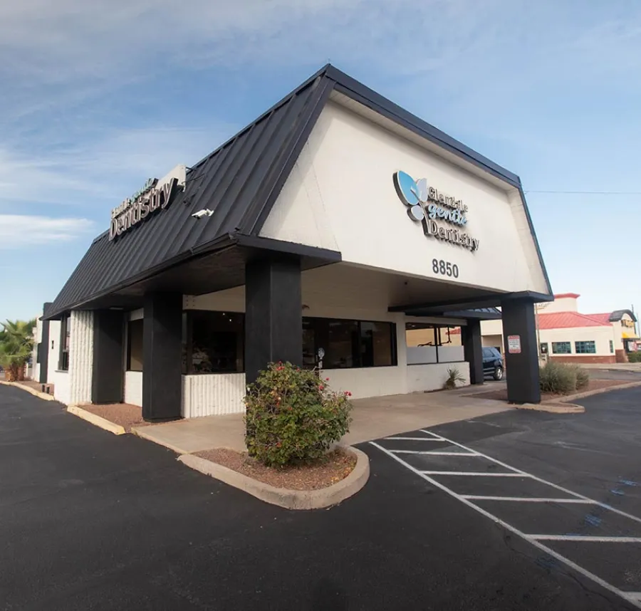 Modern dental office building with black and white exterior and parking lot under blue sky
